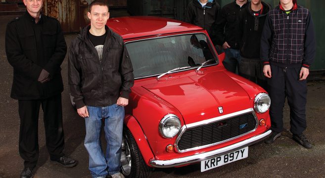 Automotive students and lecturer standing next to their restored red Mini