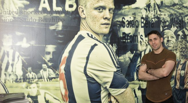 Photography student stands in front of his mural created for WBA Academy