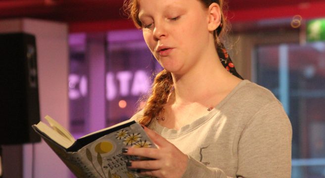 Student reading poetry out from a book