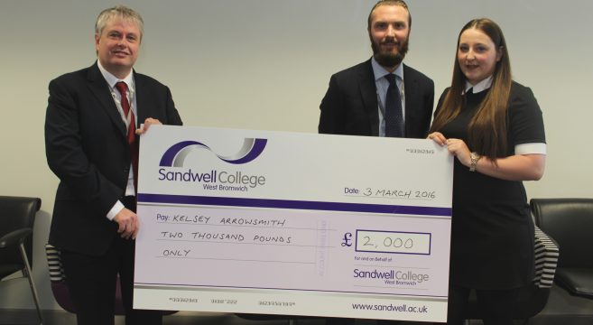 Two male staff and female student holding giant cheque