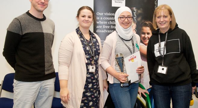 Award winner holding trophy with three presenters