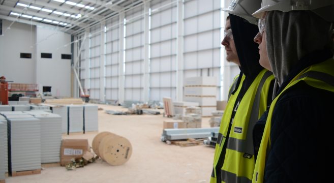 Two construction students wearing hard hats at site