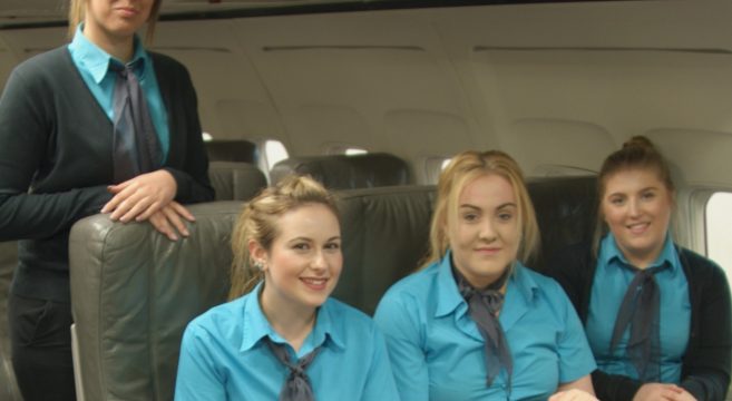 Four female travel students in aircraft cabin