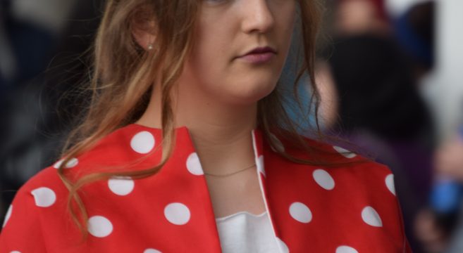 Fashion show model wearing red and white polka dot jacket