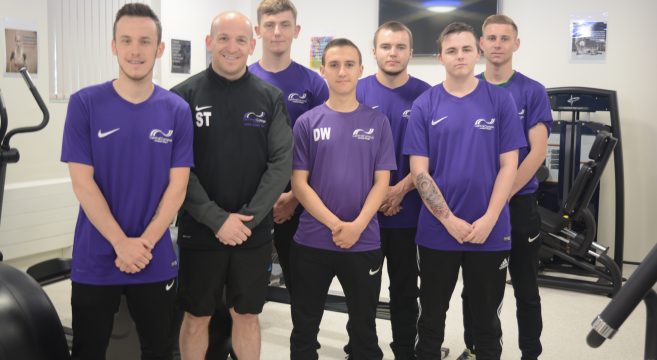 Sport lecturer with six male students in gym