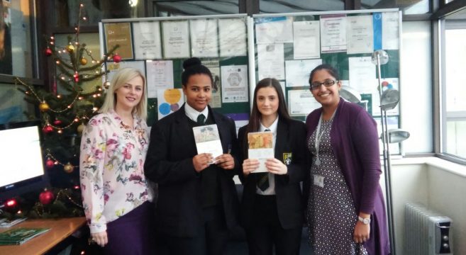 Two female secondary school students showing their calendar design that won an award pictured with staff members