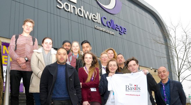 A group of students pictured outside Sandwell College campus, male student holding white St Basils t-shirt