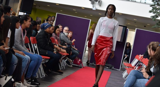 Female student walking down model runway