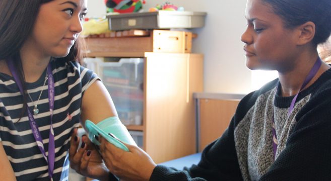 Female student taking blood pressure of another female student