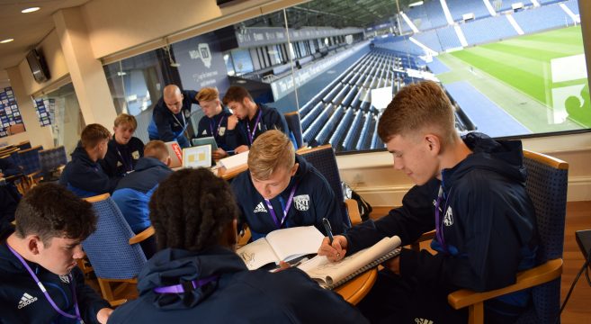 Male Sport students making notes at a table
