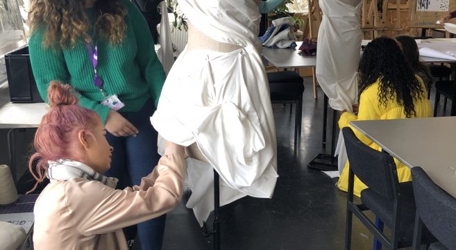 Students placing fabric on mannequin