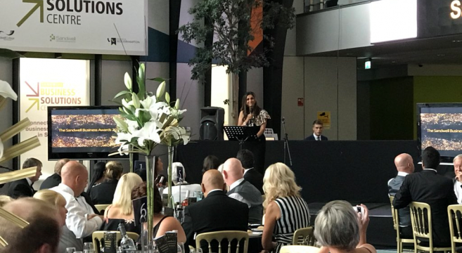 Female speaker in front of audience sat down at table