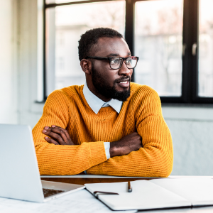 Male student in yellow jumper at work desk