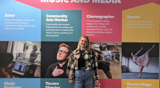 Performing arts female student standing in front of wall display