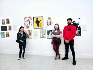 Art students standing in front of their work at the gallery