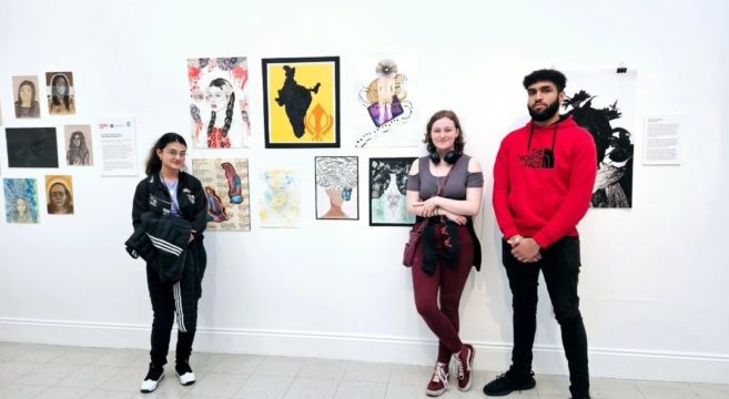 Art students standing in front of their work at the gallery