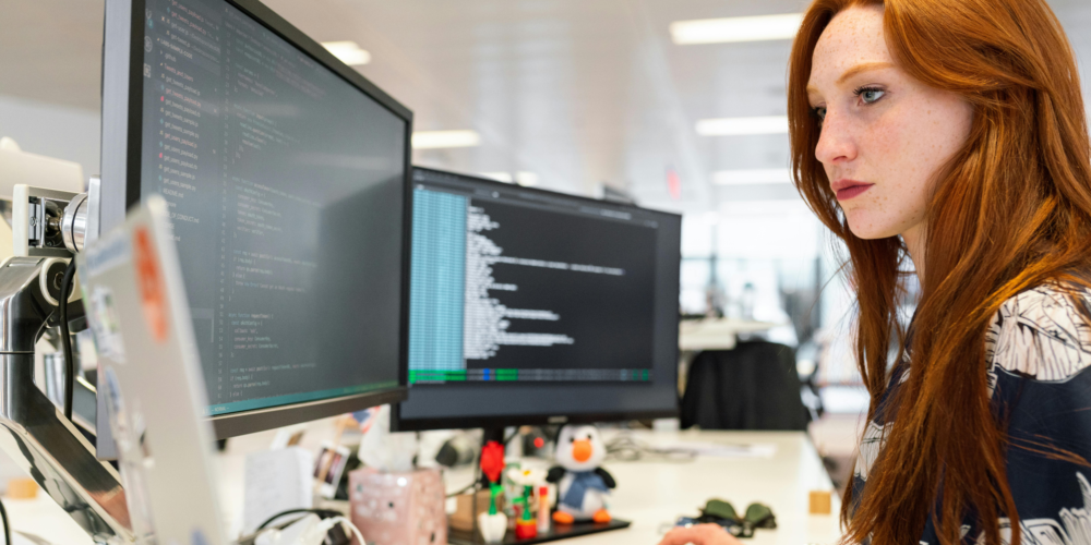 Lady coding on two desktop screens