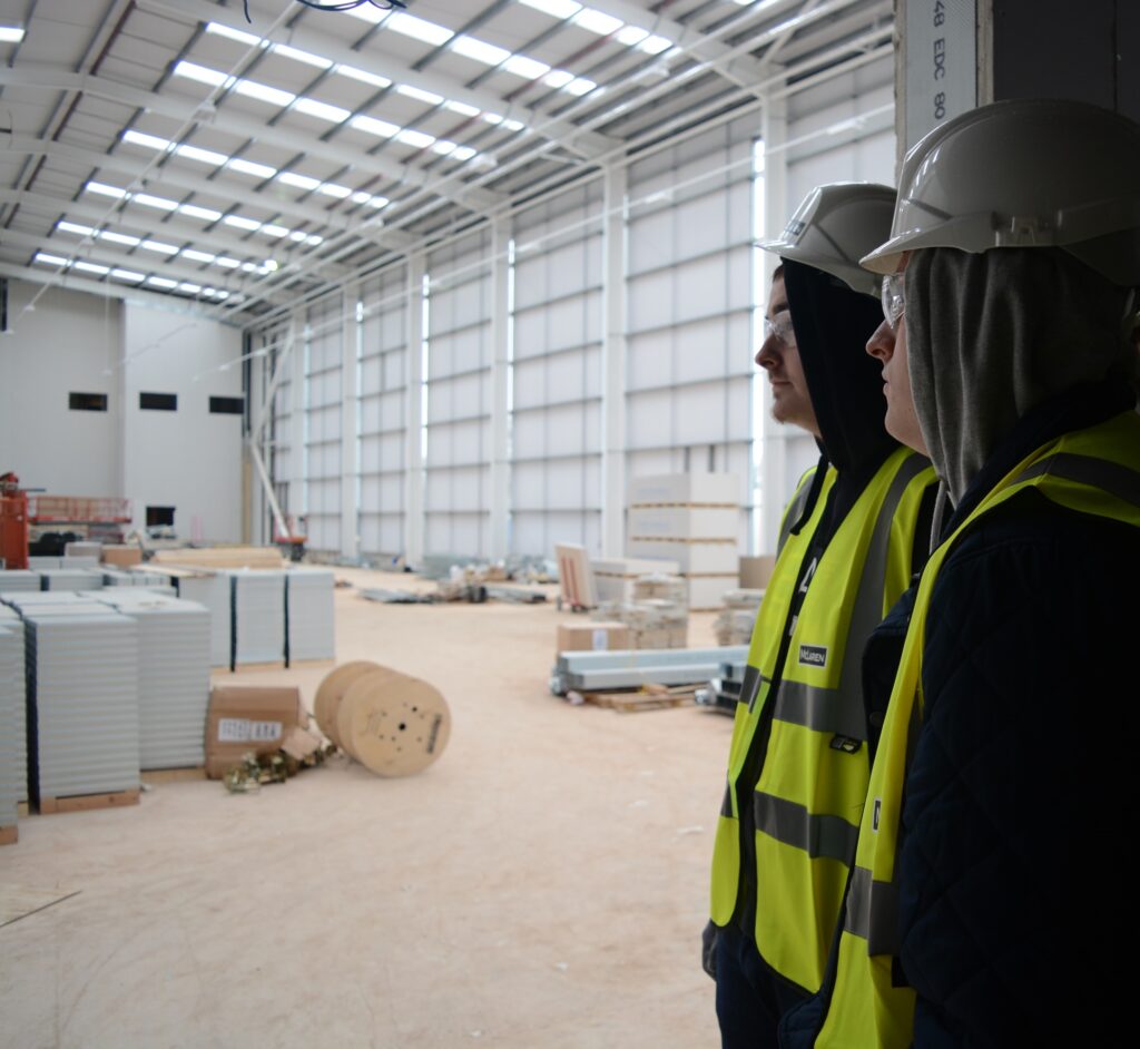 Two construction students wearing hard hats at site
