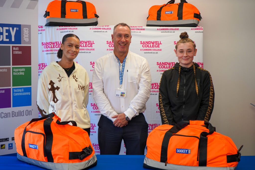 Female apprentices and male employer with orange work bags