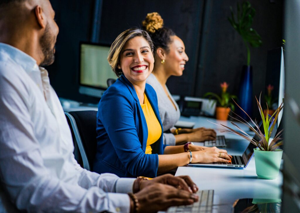Three people working at computers and lady smiling