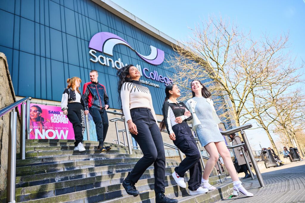 Students walking down the steps of Sandwell college smiling