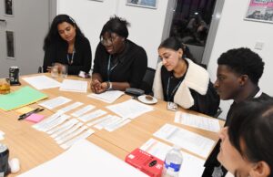 Panel of students round table looking at materials