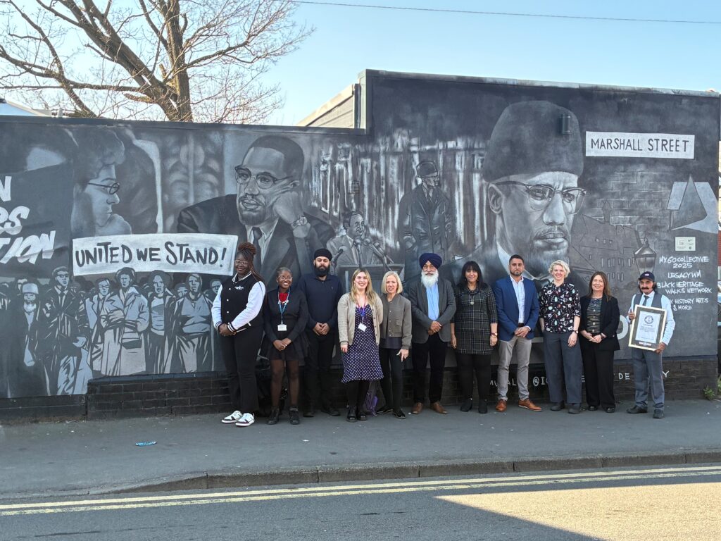 Two students in line of people in front of Smethwick mural