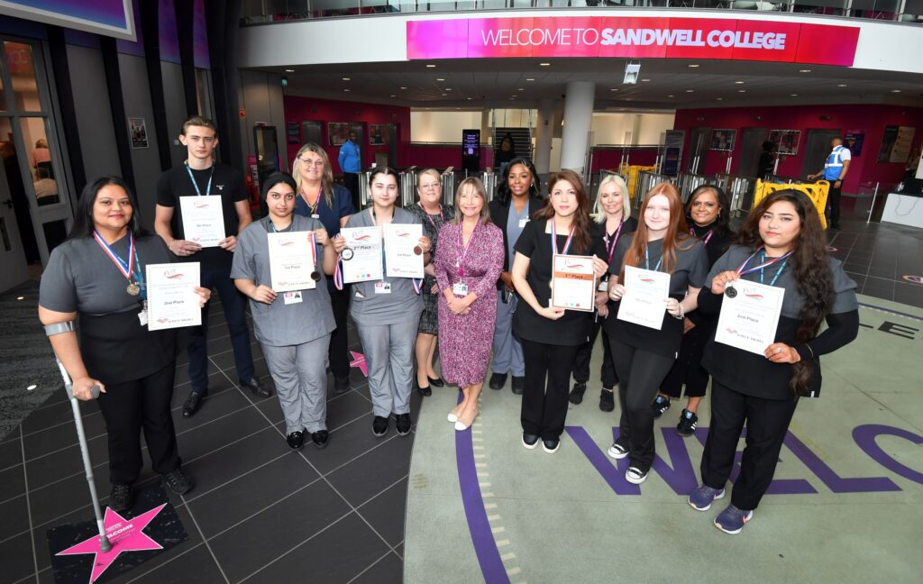 Award winners holding their certificates with college principal and staff in atrium