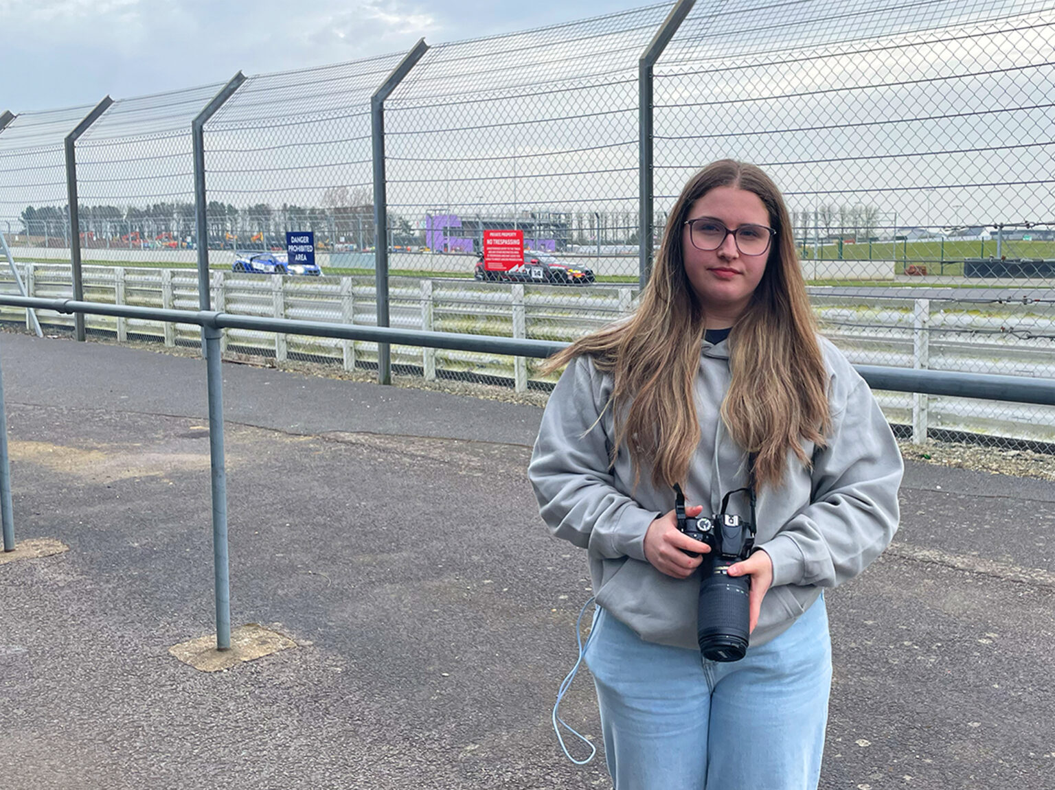 Photography student holding camera at race track