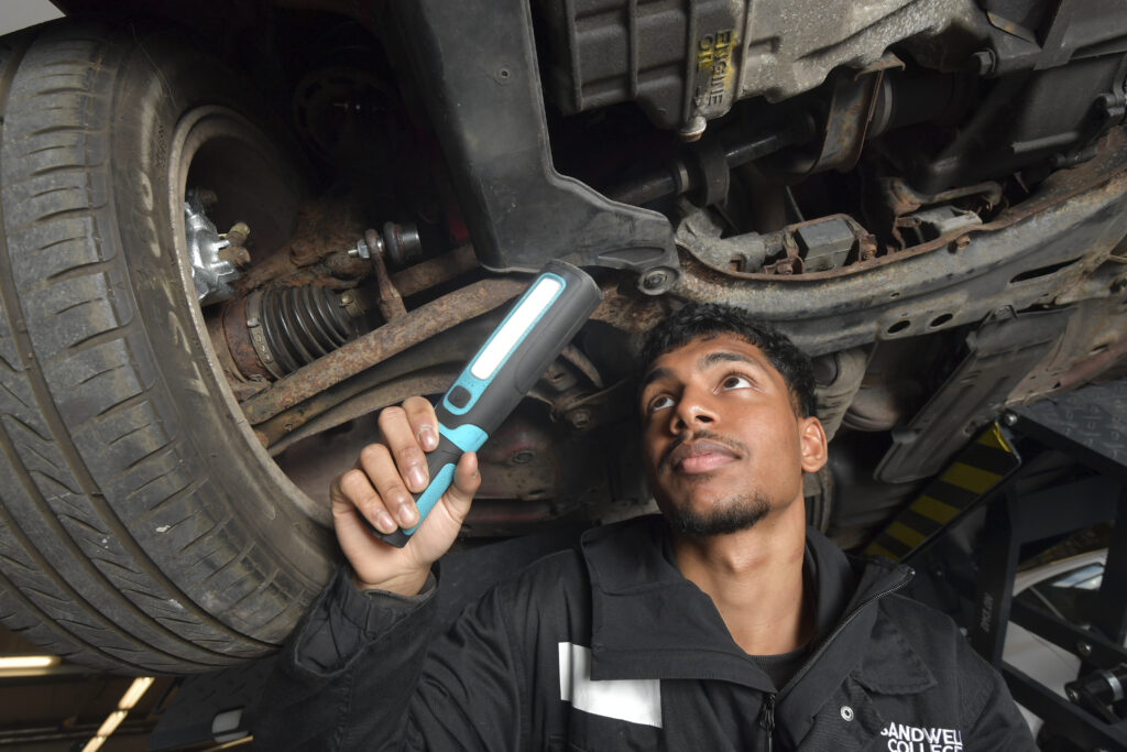 Student shining torch on car